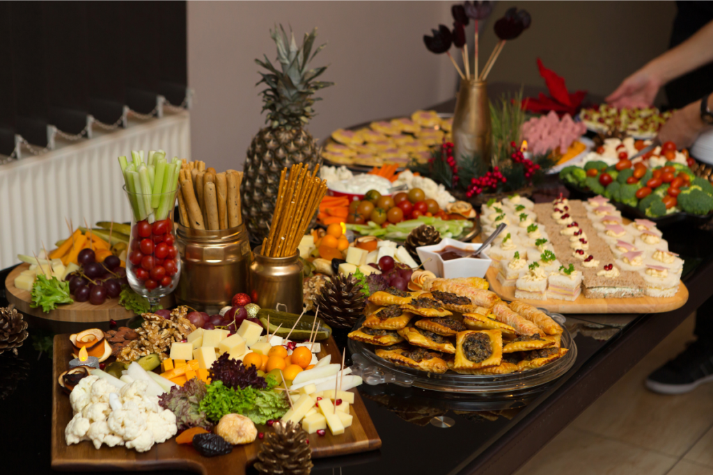 A festive table filled with a variety of party snacks, including vegetables, fruits, cheeses, sandwiches, and baked pastries