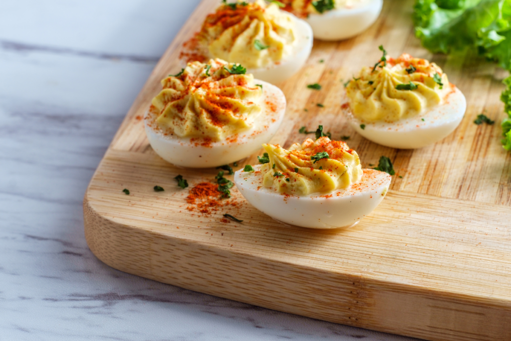 A close-up of deviled eggs on a platter, garnished with paprika and fresh parsley.