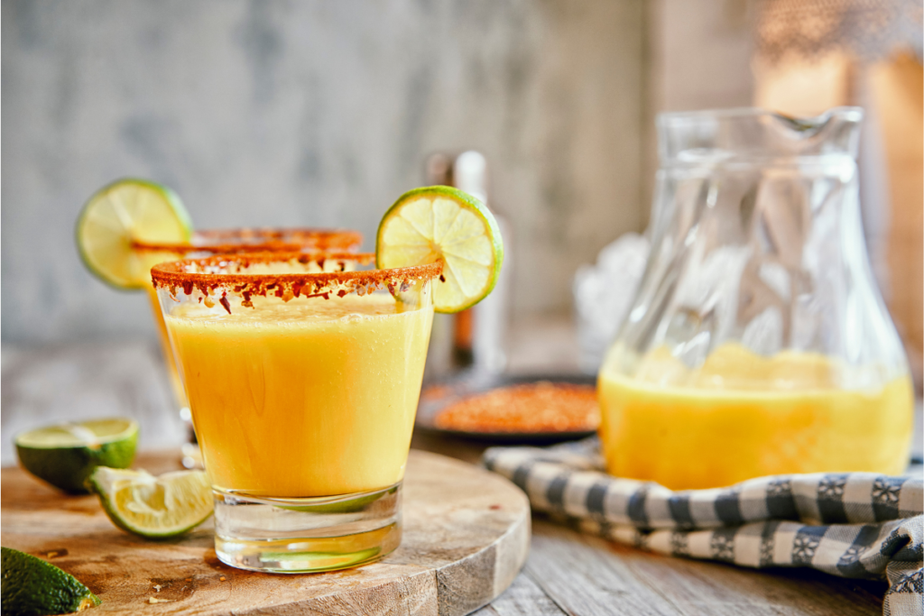 A vibrant image of a freshly made mango margarita in a traditional margarita glass with a salted rim, lime wedge