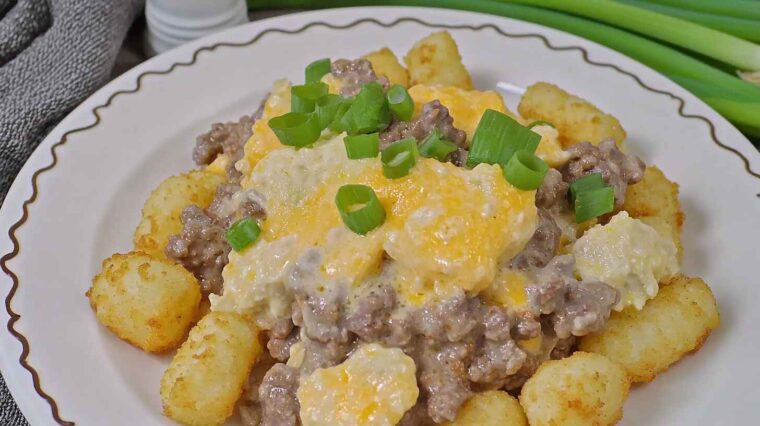 Slow Cooker Cowboy Casserole Recipe: A Hearty, Budget-Friendly Comfort Food for Busy Nights 6 Plate of Slow Cooker Cowboy Casserole with tater tots, ground beef, melted cheese, and green onions.