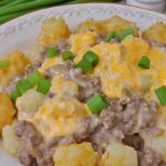 Slow Cooker Cowboy Casserole Recipe: A Hearty, Budget-Friendly Comfort Food for Busy Nights 5 A plate of Slow Cooker Cowboy Casserole featuring tater tots, ground beef, creamy sauce, melted cheese, and green onion garnish.