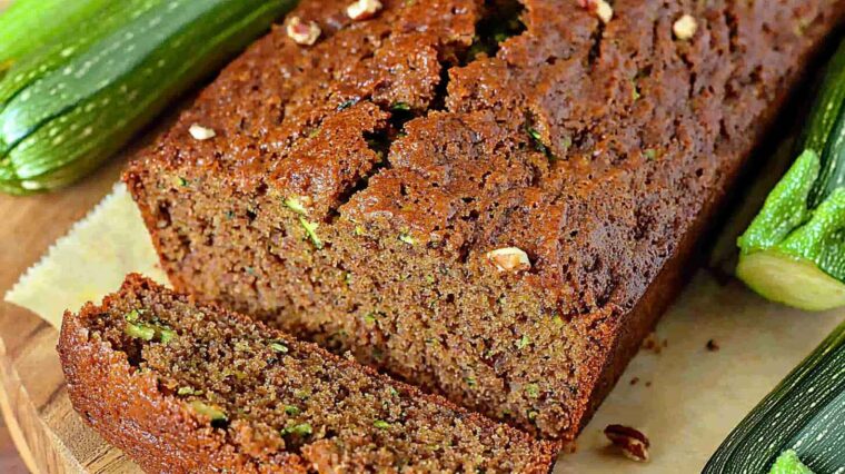 Zucchini Bread: Moist, Spiced, and Absolutely Irresistible 4 Sliced zucchini bread with nuts on a wooden board, with fresh zucchinis