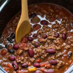 Slow Cooker Chili Recipe: The Ultimate Set-and-Forget Comfort Food 6 chili with beans and ground beef in a slow cooker, stirred with a wooden spoon