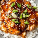 Honey Garlic Slow Cooker Chicken Thighs: Easy Flavorful Dinner Recipe 5 Bowl of honey garlic slow cooker chicken thighs served over white rice, topped with green onions and sesame seeds.